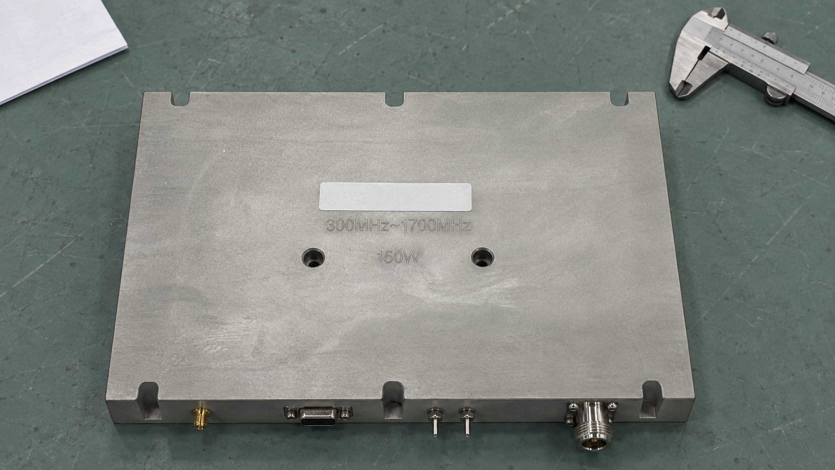 RF amplifier module on a work mat beside a caliper for visual and mechanical checks.