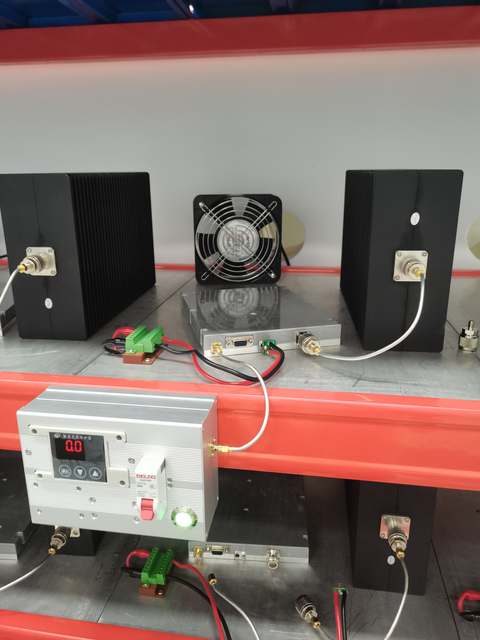 Amplifier modules connected on a rack shelf with a cooling fan, finned RF loads and power wiring.
